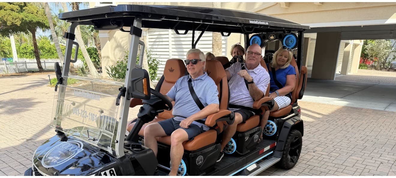 Friends riding a black Hodo's golf cart in an AMI driveway
