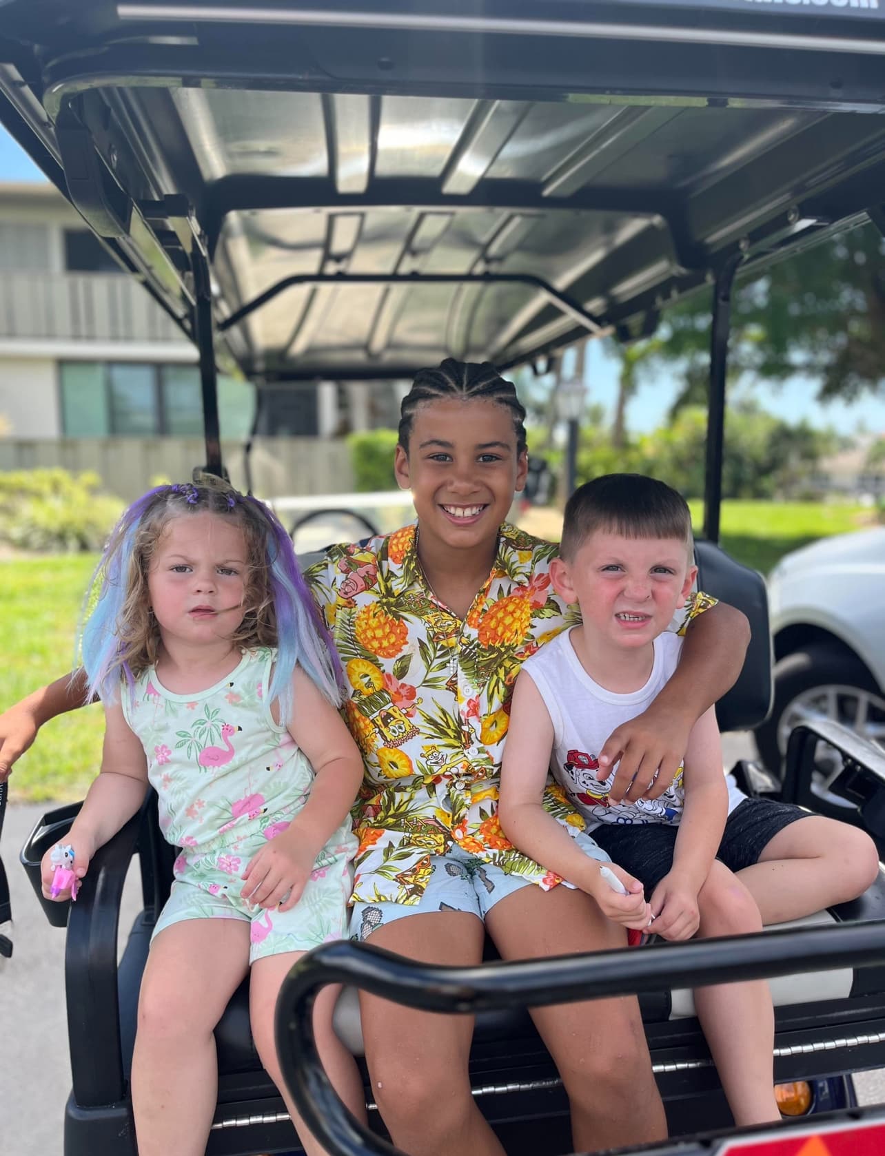 Three happy kids riding a Hodo's golf cart