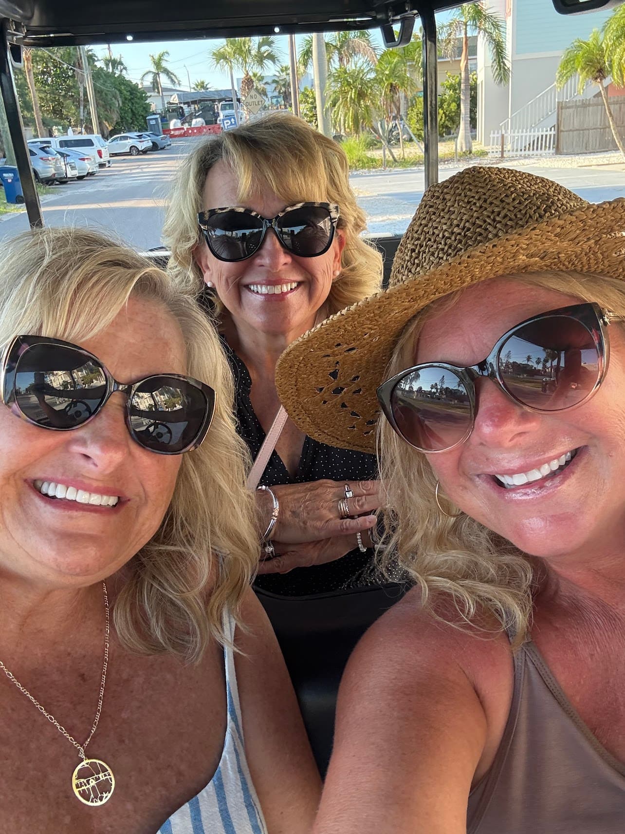 Three friends smiling in a Hodo's golf cart on Anna Maria Island