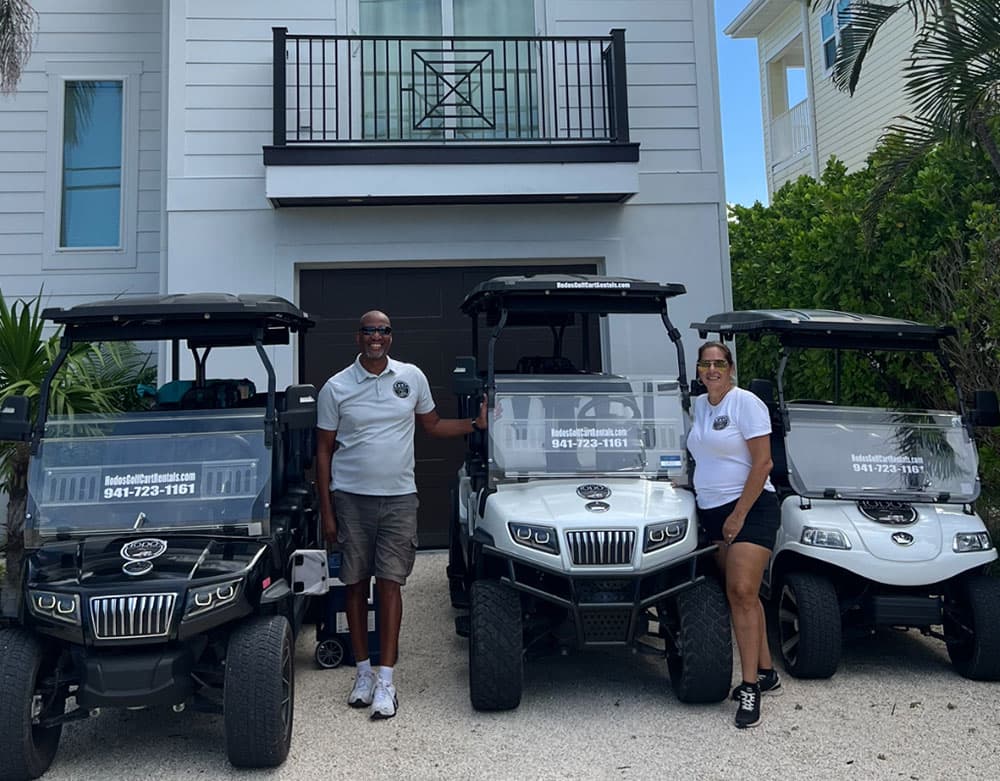 The Hodo's team standing with their fleet of golf carts in front of an Anna Maria Island home